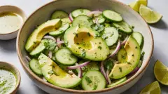 Close-up of freshly tossed avocado and cucumber salad with herbs.